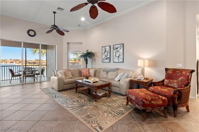 living room featuring a ceiling fan, visible vents, crown molding, and a towering ceiling