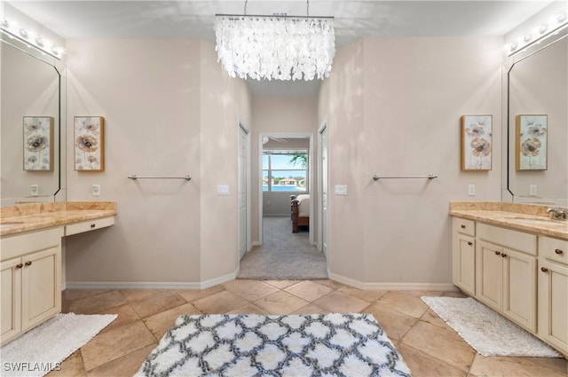 ensuite bathroom featuring tile patterned flooring, baseboards, a chandelier, and vanity