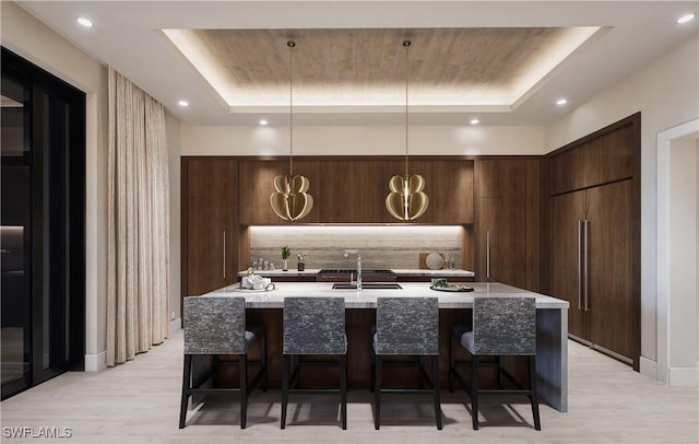 kitchen featuring a sink, a tray ceiling, modern cabinets, and a breakfast bar