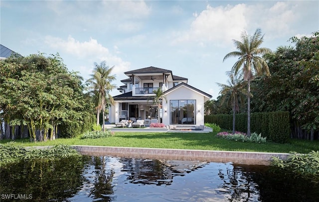 rear view of property featuring a balcony, a patio area, and a lawn