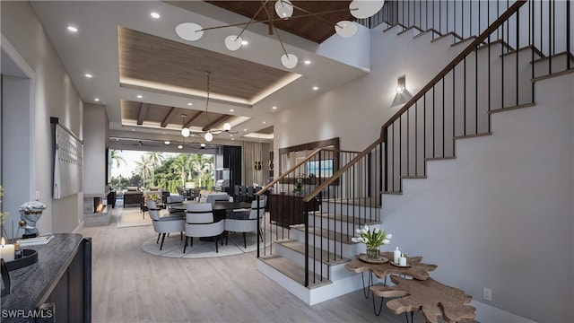 interior space with a tray ceiling, recessed lighting, wood finished floors, and a towering ceiling