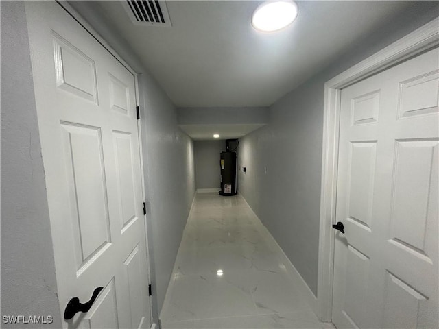 hallway with water heater, marble finish floor, visible vents, and baseboards