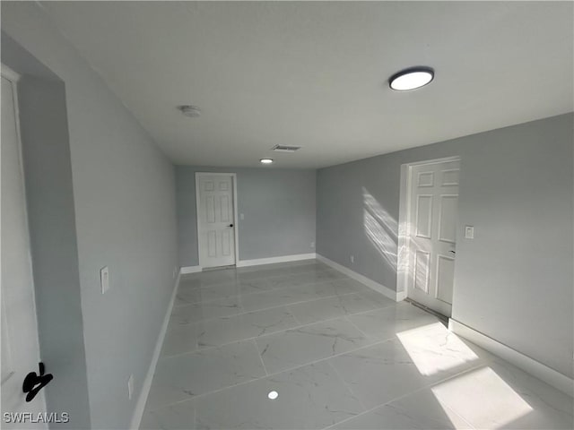 empty room featuring marble finish floor and baseboards