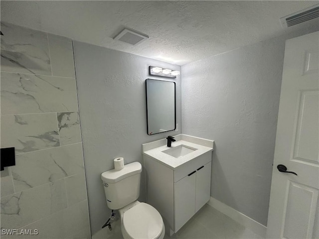 bathroom featuring visible vents, vanity, toilet, and a textured ceiling