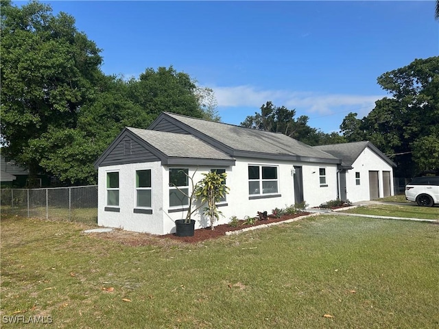 view of front of property with roof with shingles, stucco siding, an attached garage, fence, and a front lawn