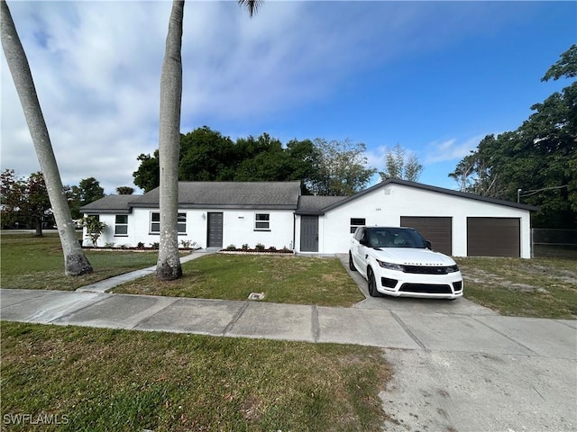 view of front of property featuring a garage, concrete driveway, a front yard, and stucco siding