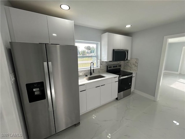 kitchen featuring appliances with stainless steel finishes, a sink, marble finish floor, white cabinetry, and backsplash