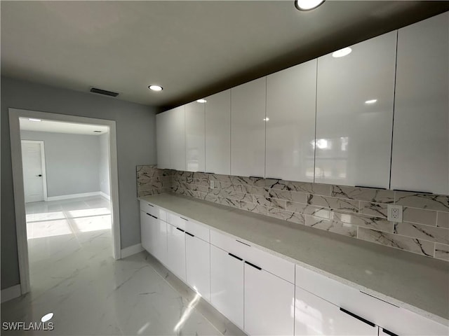 kitchen with marble finish floor, visible vents, decorative backsplash, white cabinetry, and modern cabinets