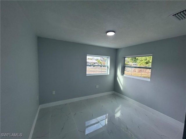 unfurnished room with marble finish floor, visible vents, a textured ceiling, and baseboards