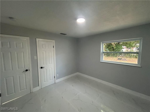 unfurnished room featuring marble finish floor, visible vents, and baseboards