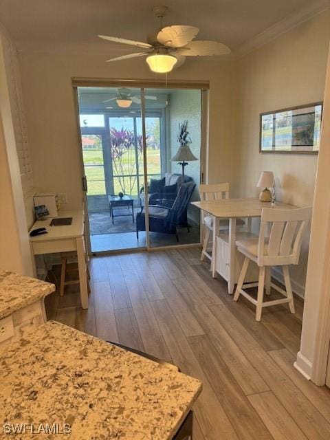 dining space with a ceiling fan, crown molding, and wood finished floors