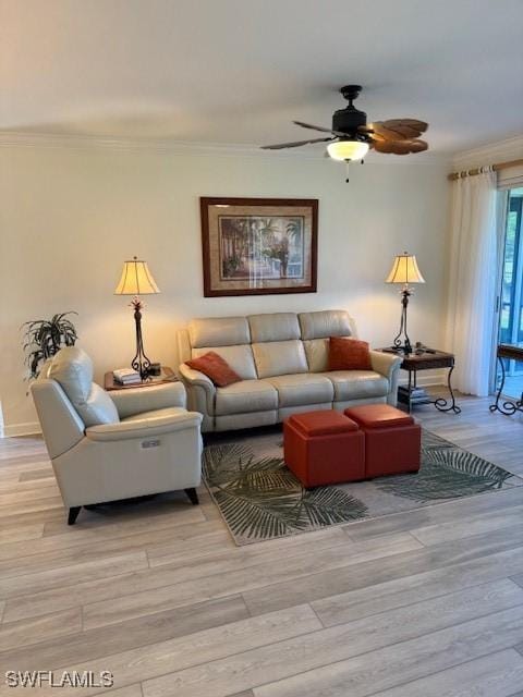 living area with ornamental molding, a ceiling fan, and light wood-style floors