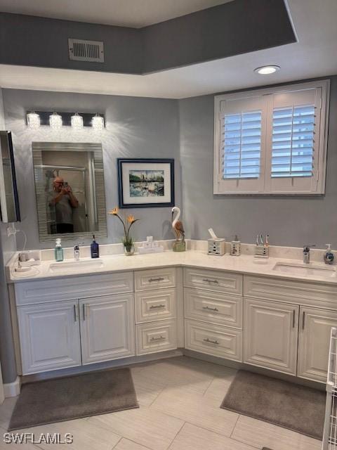 bathroom with a stall shower, visible vents, a sink, and double vanity