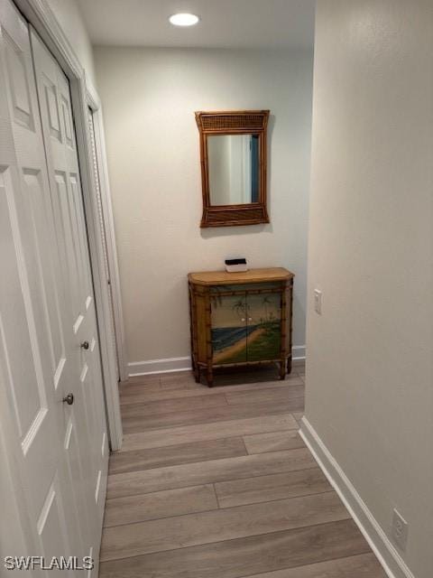 corridor featuring baseboards, wood finished floors, and recessed lighting