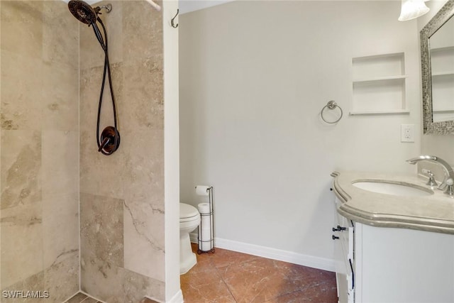 full bath featuring toilet, a tile shower, vanity, and baseboards