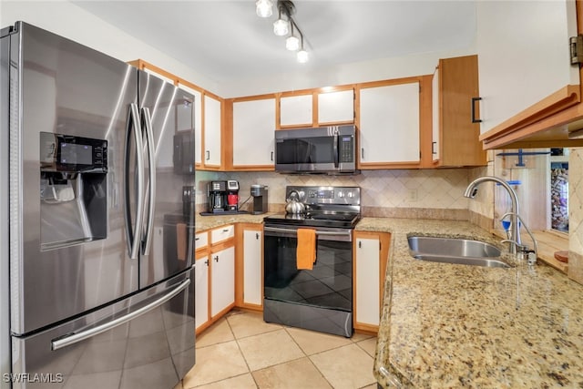 kitchen with light stone counters, light tile patterned floors, stainless steel appliances, backsplash, and a sink