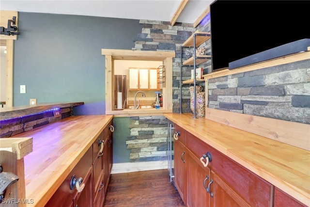 bar featuring a sink, beamed ceiling, and dark wood finished floors