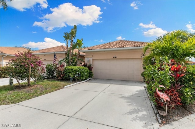 view of front of home featuring an attached garage, a tiled roof, concrete driveway, and stucco siding