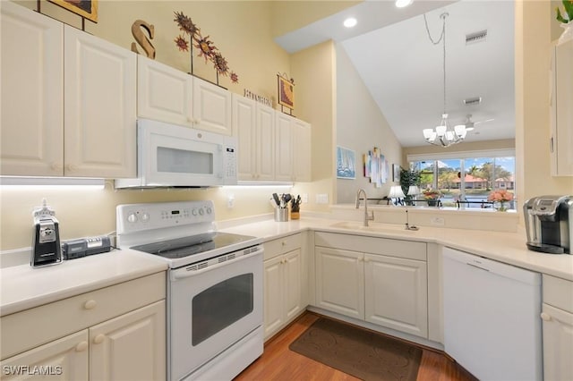 kitchen featuring a sink, white appliances, an inviting chandelier, lofted ceiling, and visible vents