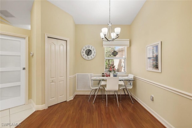 dining area with baseboards, wood finished floors, visible vents, and a notable chandelier