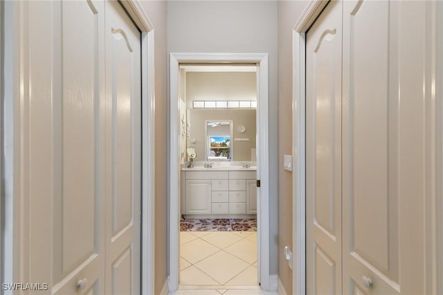 hall featuring a sink and light tile patterned floors