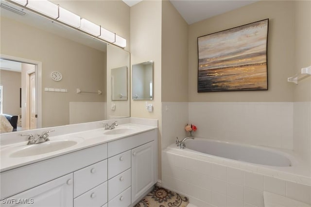 bathroom featuring a garden tub, double vanity, a sink, and visible vents