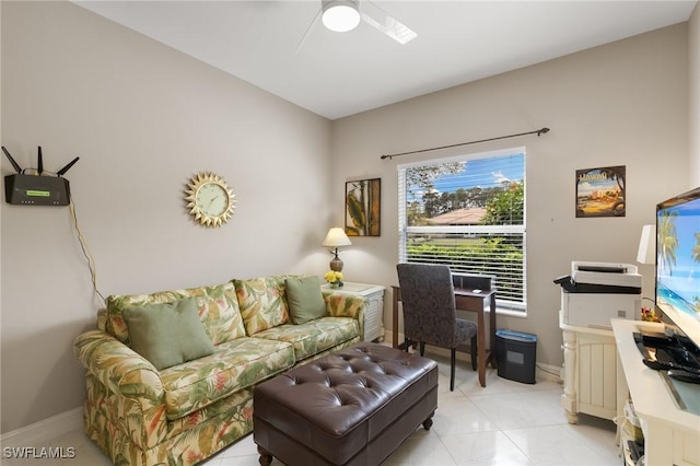 living area with baseboards and ceiling fan