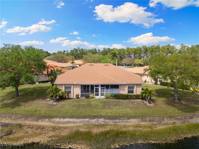 view of front of house featuring a sunroom, a tile roof, a front lawn, and stucco siding