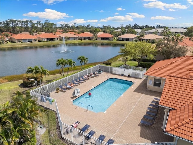 pool with a patio, a water view, fence, and a residential view