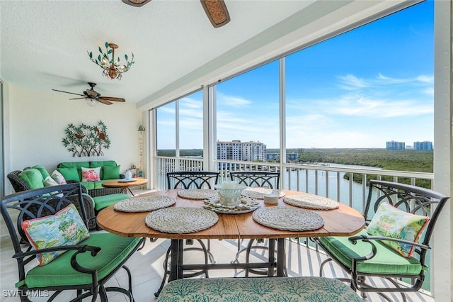 sunroom with a water view, a city view, and a ceiling fan