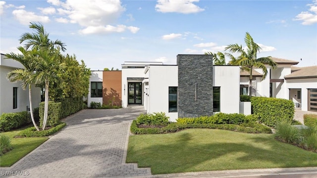 view of front facade with a front yard, decorative driveway, and stucco siding