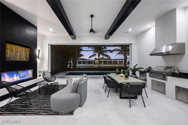 home theater featuring a glass covered fireplace and beam ceiling