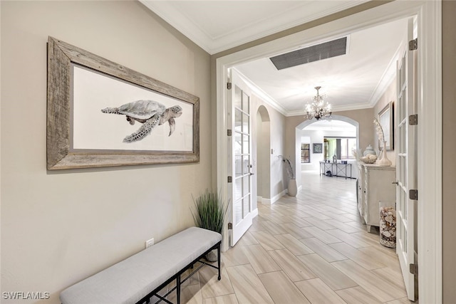 hall with baseboards, visible vents, arched walkways, ornamental molding, and a notable chandelier