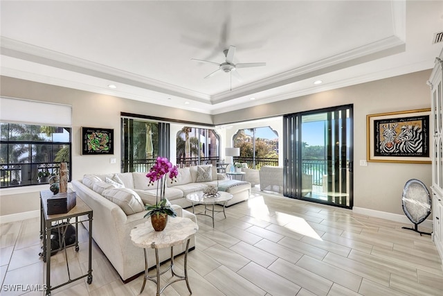 living area featuring a raised ceiling, plenty of natural light, a ceiling fan, and crown molding