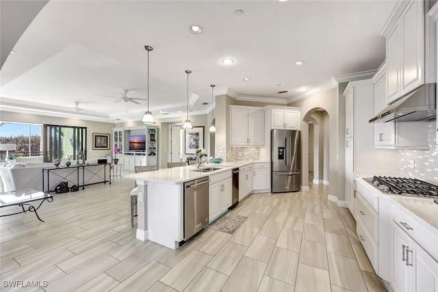 kitchen featuring arched walkways, stainless steel appliances, open floor plan, white cabinetry, and a peninsula