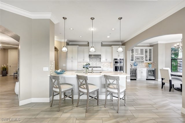 kitchen with beverage cooler, stainless steel double oven, a sink, and under cabinet range hood