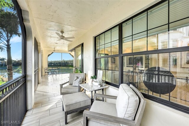 sunroom / solarium featuring a water view and ceiling fan