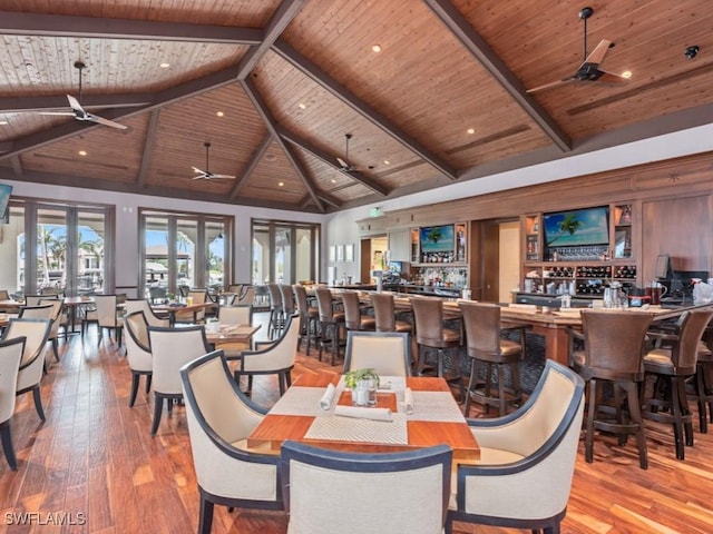 dining space featuring a ceiling fan, hardwood / wood-style flooring, wood ceiling, beamed ceiling, and wet bar