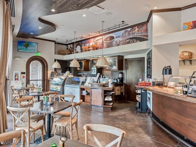 dining space featuring a high ceiling, wet bar, recessed lighting, and crown molding