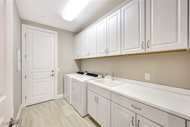 clothes washing area featuring separate washer and dryer, a sink, cabinet space, and baseboards