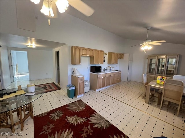 kitchen with a ceiling fan, freestanding refrigerator, light countertops, light floors, and high vaulted ceiling