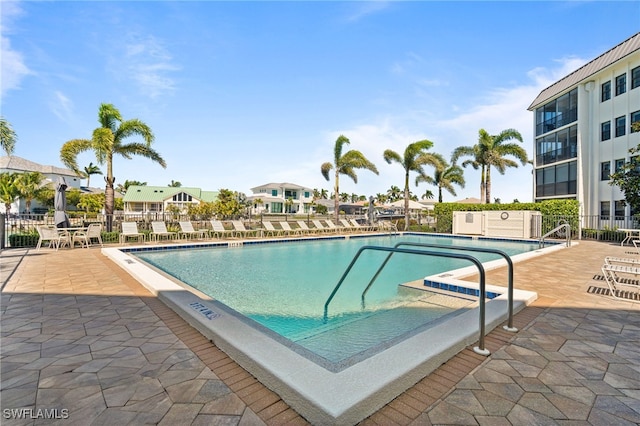 community pool with a patio area and fence