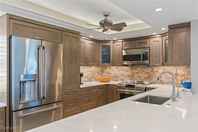 kitchen featuring appliances with stainless steel finishes, glass insert cabinets, a sink, and tasteful backsplash