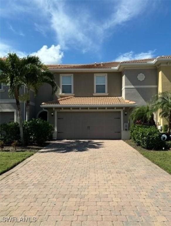 view of front of property featuring decorative driveway, a tiled roof, an attached garage, and stucco siding