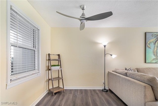 sitting room with dark wood-style floors, a textured ceiling, baseboards, and a ceiling fan