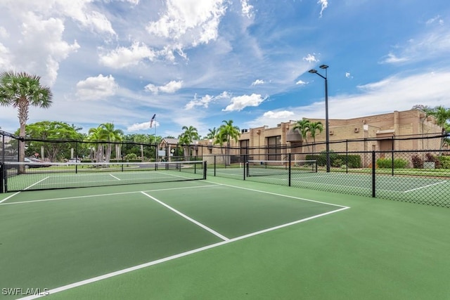 view of tennis court featuring a residential view and fence