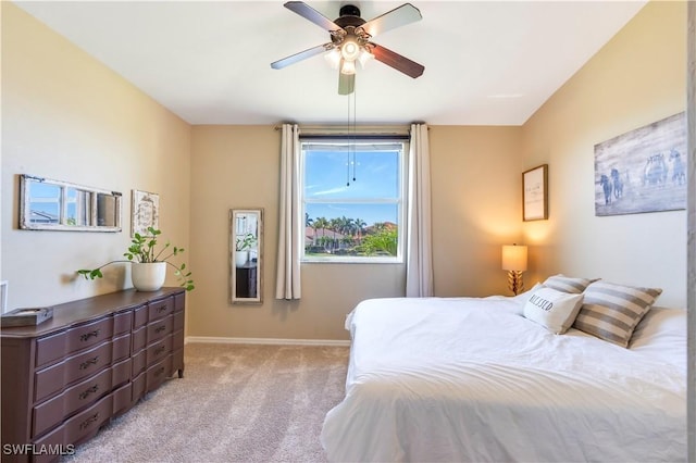 bedroom featuring light carpet, a ceiling fan, and baseboards