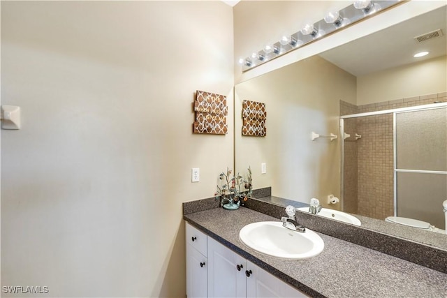 bathroom featuring visible vents, toilet, a stall shower, and vanity