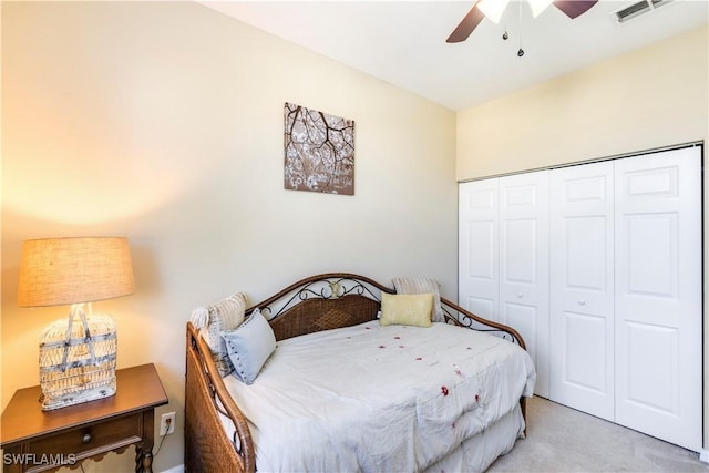 bedroom with a closet, visible vents, light colored carpet, and ceiling fan