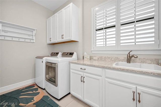 washroom featuring light tile patterned floors, baseboards, cabinet space, separate washer and dryer, and a sink